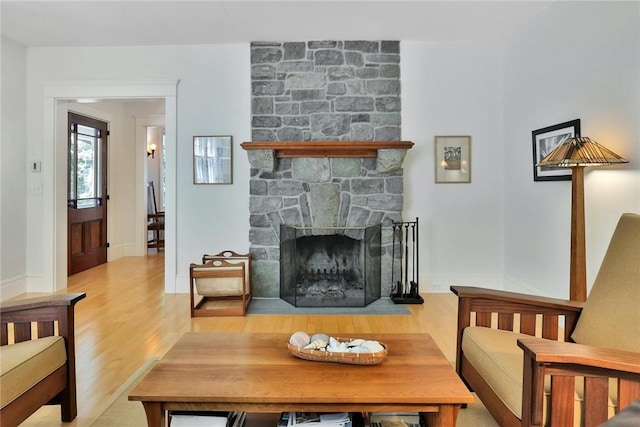 living room featuring a stone fireplace and light hardwood / wood-style floors