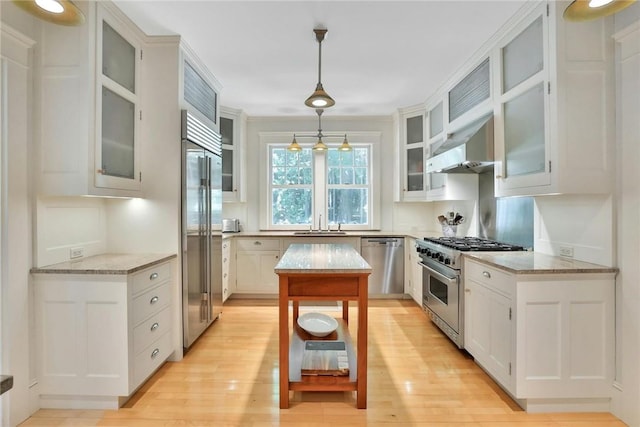 kitchen featuring decorative light fixtures, white cabinetry, high quality appliances, and light hardwood / wood-style floors