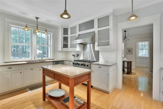 kitchen featuring sink, wall chimney range hood, decorative light fixtures, white cabinets, and light hardwood / wood-style floors