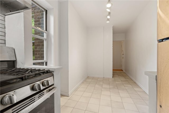 kitchen with stainless steel range with gas cooktop, light tile patterned flooring, range hood, and rail lighting