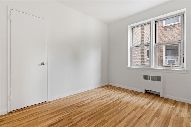 empty room with radiator heating unit and light hardwood / wood-style floors