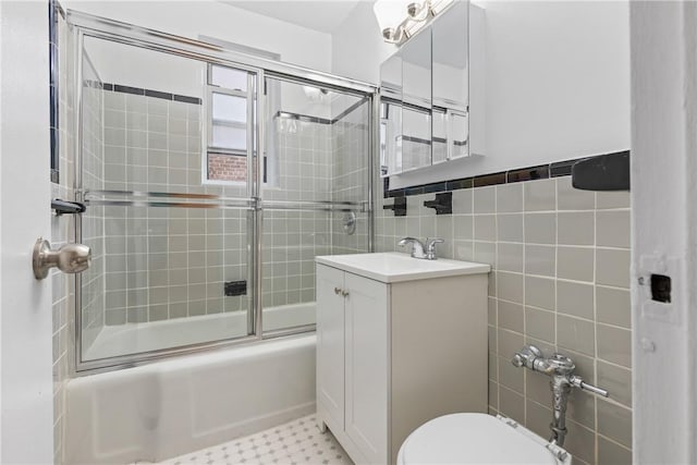 full bathroom with toilet, vanity, tile walls, and combined bath / shower with glass door