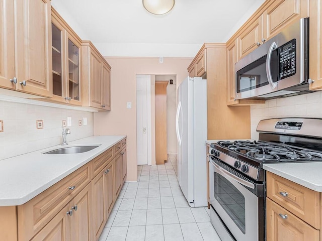 kitchen with sink, backsplash, light brown cabinetry, light tile patterned floors, and appliances with stainless steel finishes