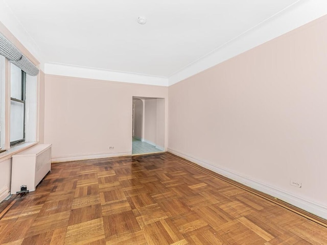 unfurnished room featuring radiator heating unit, ornamental molding, and parquet flooring