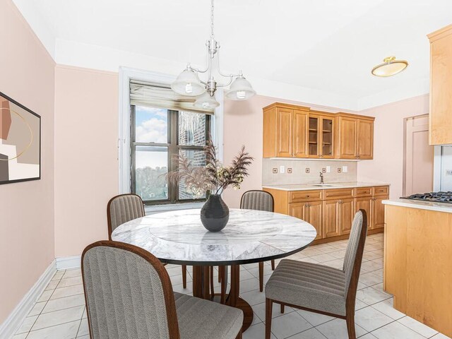 tiled dining space featuring sink and a chandelier