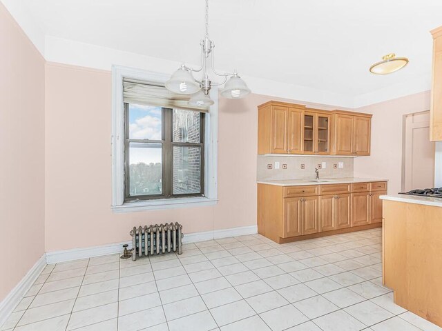 kitchen with light tile patterned flooring, sink, hanging light fixtures, and a chandelier