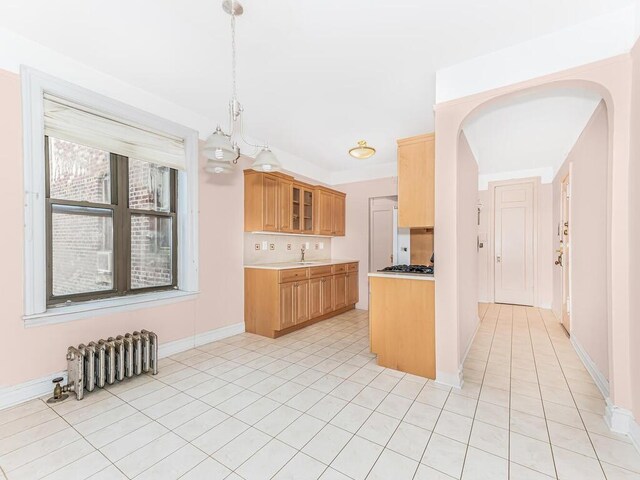 kitchen with radiator, sink, decorative light fixtures, an inviting chandelier, and light tile patterned flooring