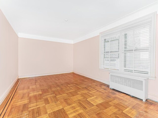 unfurnished room featuring light parquet floors, radiator, and crown molding