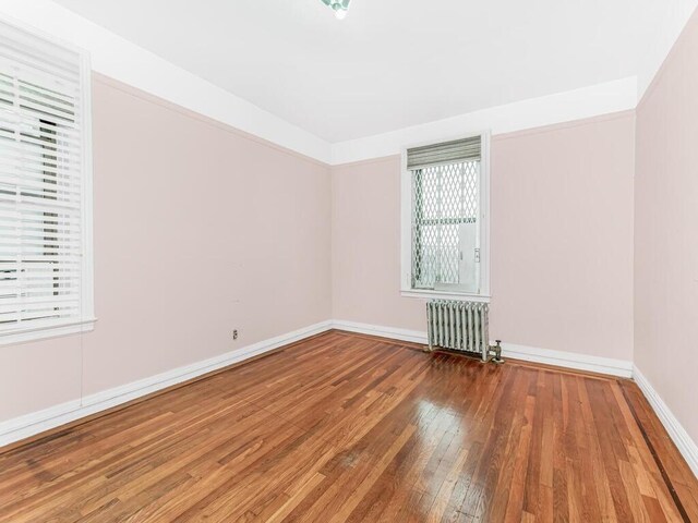 unfurnished room featuring radiator and wood-type flooring