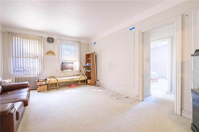 sitting room featuring light colored carpet, radiator heating unit, and crown molding