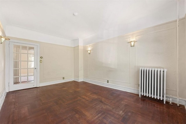 empty room with dark parquet flooring and radiator