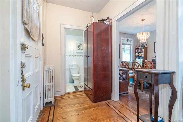 hall featuring a chandelier, hardwood / wood-style floors, and radiator heating unit