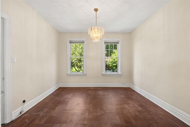 unfurnished room featuring dark parquet flooring and an inviting chandelier