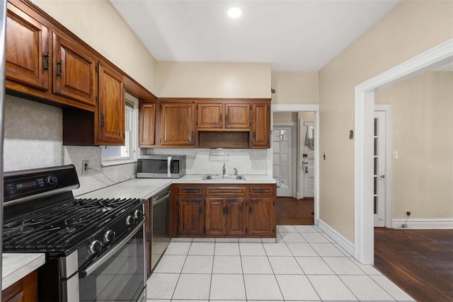 kitchen with tasteful backsplash, sink, appliances with stainless steel finishes, and light hardwood / wood-style flooring