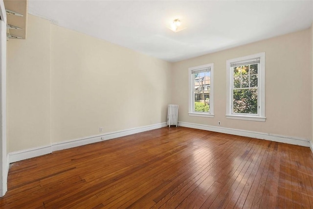 empty room featuring radiator heating unit and hardwood / wood-style flooring