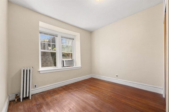 spare room with radiator heating unit, hardwood / wood-style flooring, and cooling unit