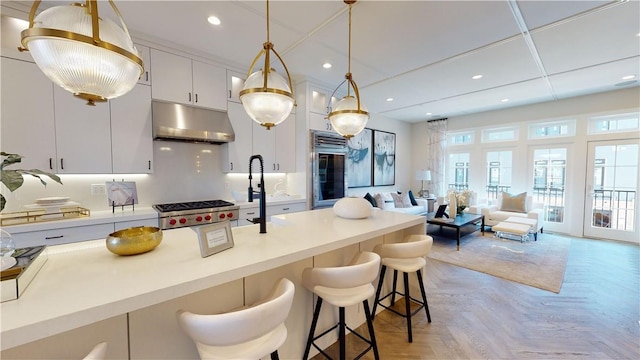 kitchen with white cabinetry, range, decorative light fixtures, a kitchen breakfast bar, and light parquet flooring