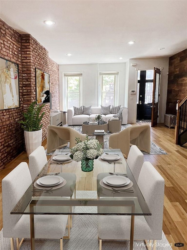 dining space with radiator heating unit, light hardwood / wood-style floors, and brick wall