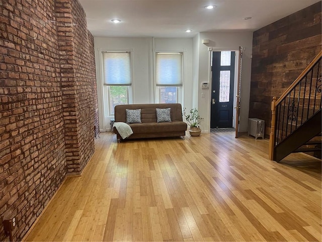 living room featuring radiator heating unit, brick wall, and light hardwood / wood-style flooring