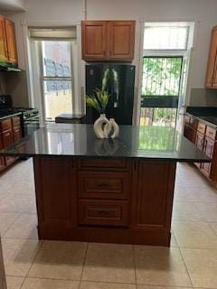 kitchen with a wealth of natural light, black refrigerator, light tile patterned flooring, and a kitchen island