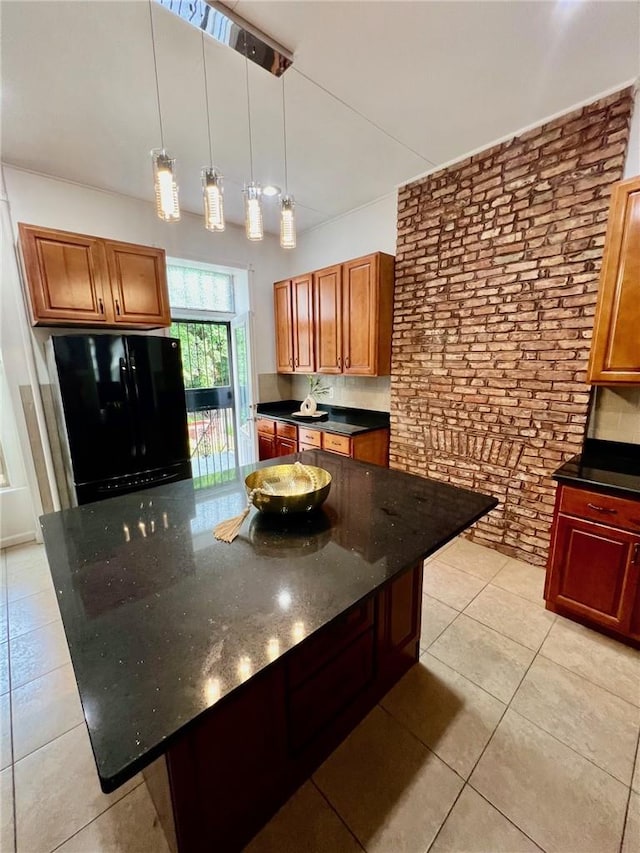 kitchen featuring black fridge, light tile patterned floors, dark stone countertops, a kitchen island, and hanging light fixtures