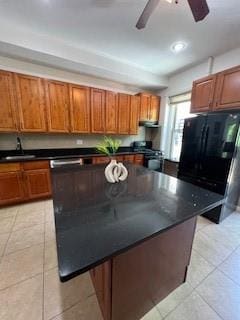 kitchen featuring ceiling fan, sink, black appliances, light tile patterned floors, and a center island