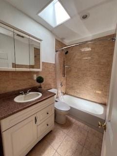 full bathroom featuring vanity, tile patterned floors, a skylight, tiled shower / bath combo, and toilet