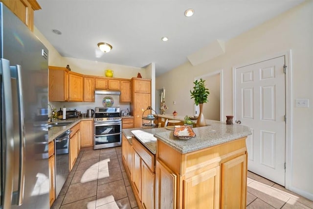 kitchen featuring sink, stainless steel appliances, light tile patterned floors, light stone counters, and a kitchen island