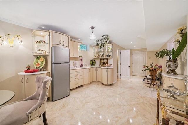 kitchen featuring cream cabinetry, decorative light fixtures, and stainless steel refrigerator