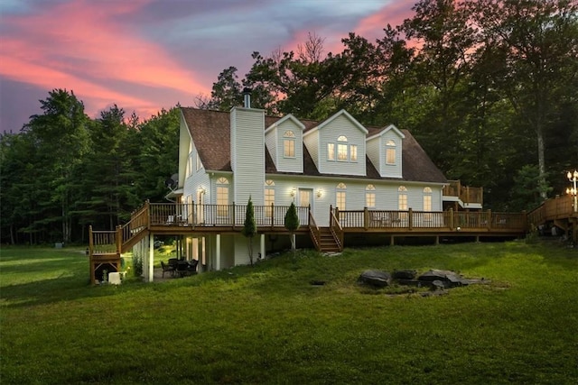 back house at dusk with a lawn and a deck