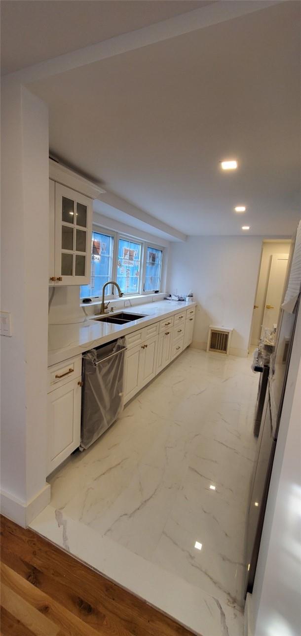 kitchen with white cabinetry, dishwasher, light hardwood / wood-style floors, and sink