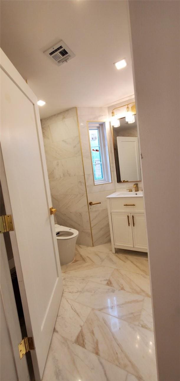 bathroom featuring vanity, toilet, and tile walls