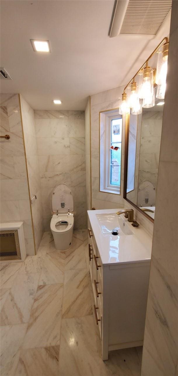 bathroom with vanity, tile walls, and toilet