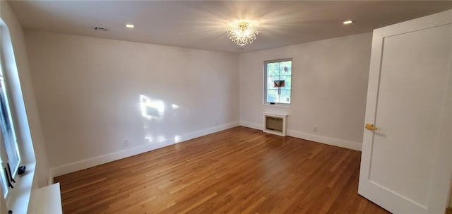 spare room with hardwood / wood-style flooring and a notable chandelier