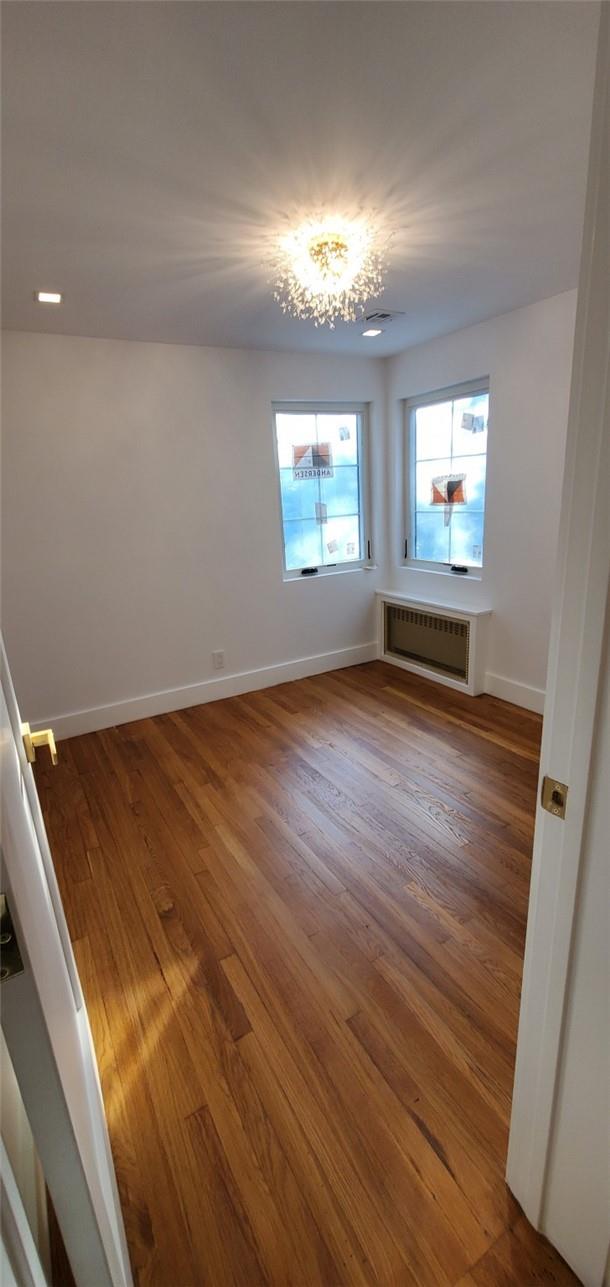 unfurnished room with radiator and hardwood / wood-style floors