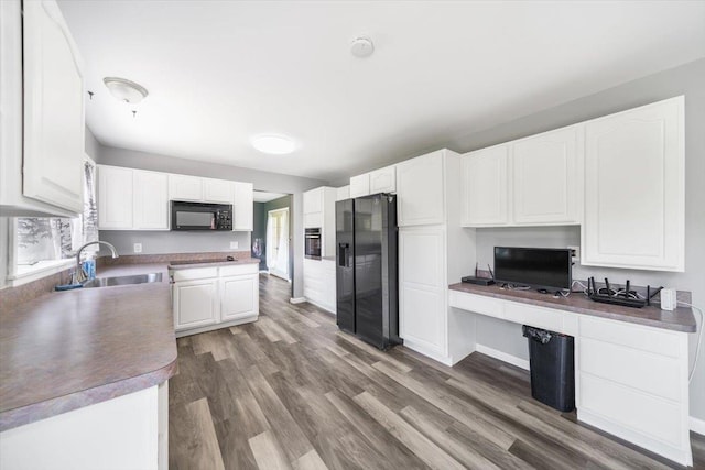 kitchen featuring dark wood-type flooring, sink, black appliances, built in desk, and white cabinetry