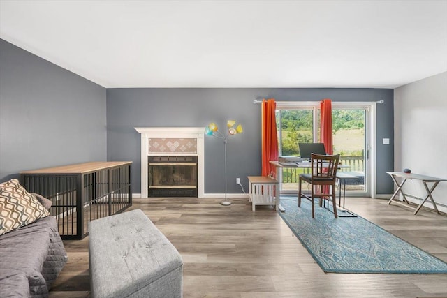 living room featuring a tiled fireplace and wood-type flooring