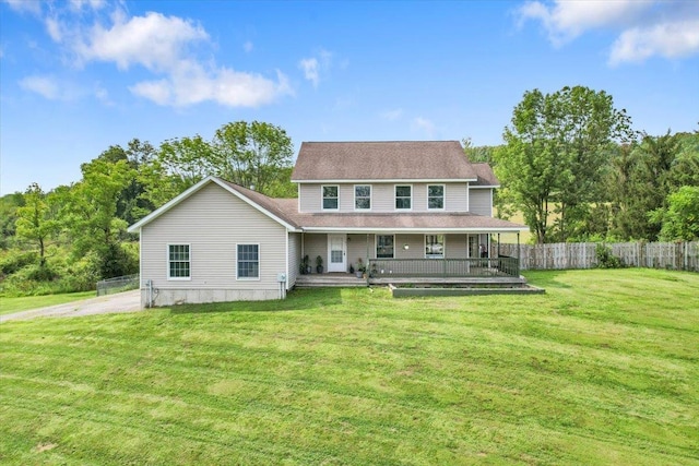 rear view of house featuring covered porch and a yard