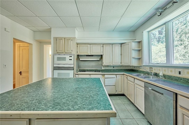 kitchen featuring stainless steel appliances, light tile patterned flooring, a center island, and a paneled ceiling