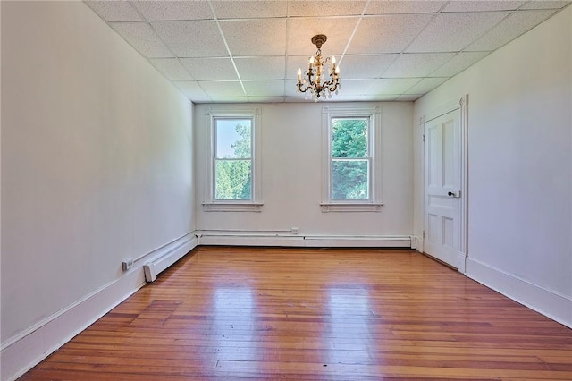 empty room with an inviting chandelier, a paneled ceiling, and wood-type flooring