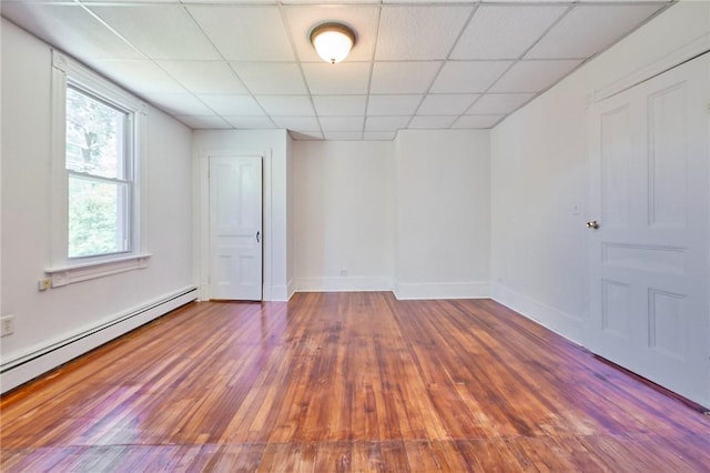 unfurnished room with a baseboard radiator, dark wood-type flooring, and a paneled ceiling