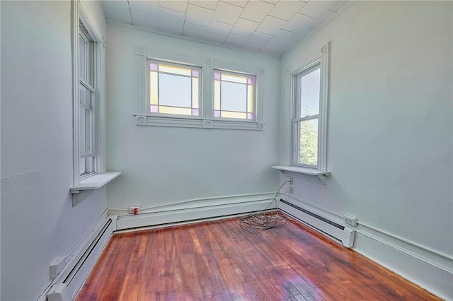 empty room with hardwood / wood-style floors and baseboard heating