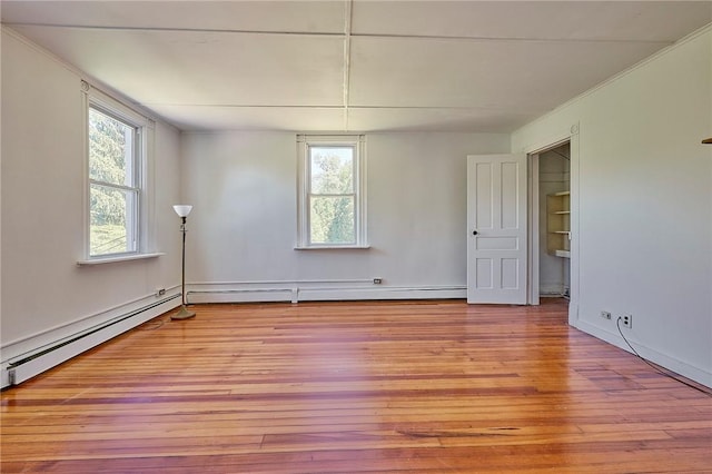 spare room with a baseboard heating unit, ornamental molding, and light hardwood / wood-style floors