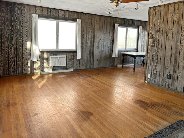 unfurnished room with a baseboard heating unit, wood-type flooring, a wall unit AC, and ceiling fan