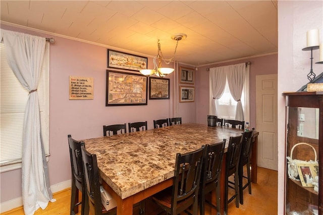 dining area with crown molding, a chandelier, and light wood-type flooring