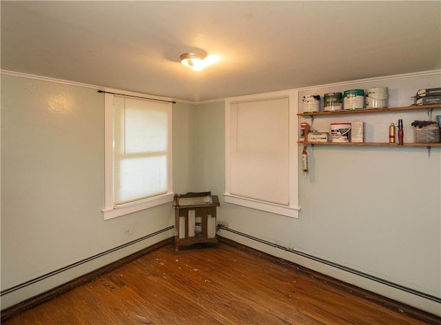 spare room featuring dark wood-type flooring and a baseboard radiator