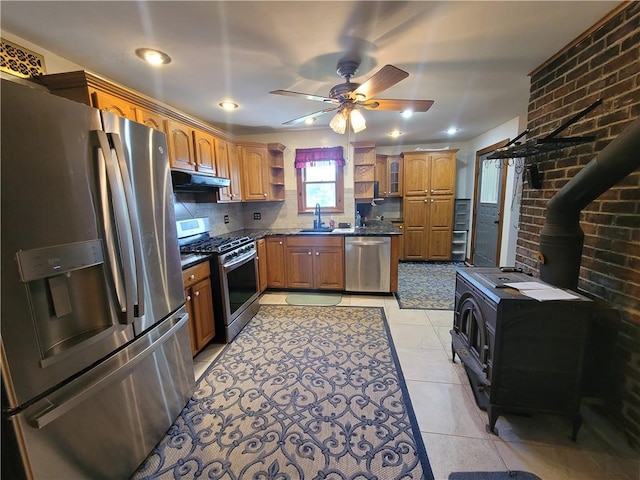 kitchen with a wood stove, sink, stainless steel appliances, tasteful backsplash, and light tile patterned flooring