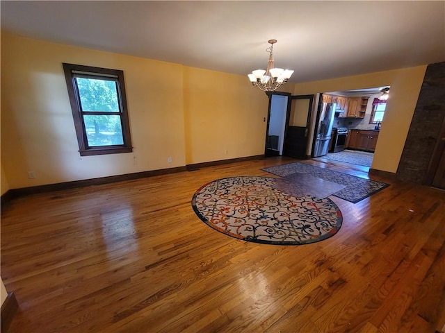 unfurnished dining area featuring a chandelier and hardwood / wood-style flooring