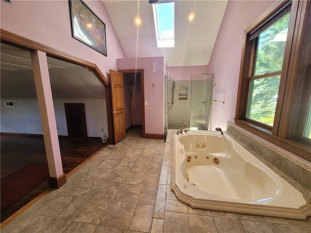 bathroom with a healthy amount of sunlight, shower with separate bathtub, high vaulted ceiling, and a skylight