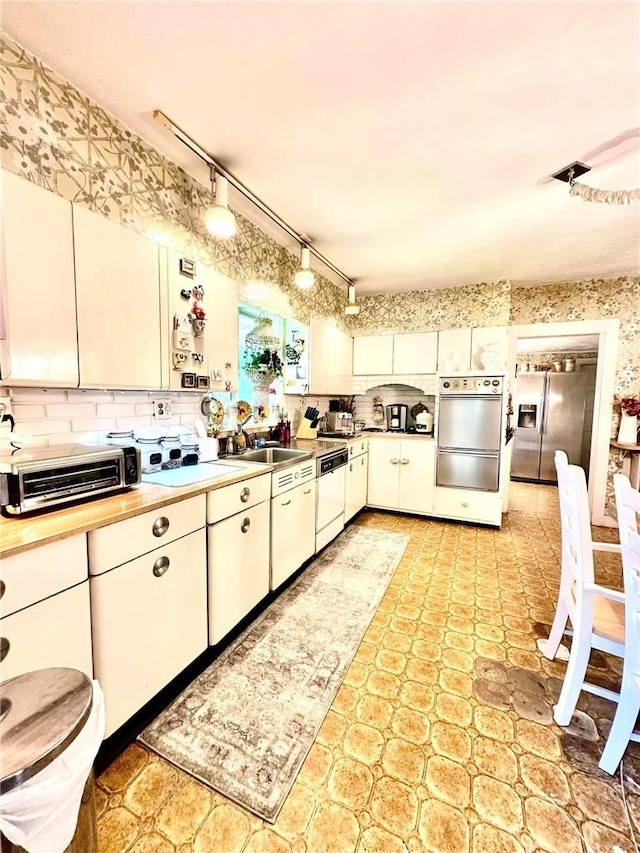 kitchen with white cabinets, stainless steel appliances, and track lighting